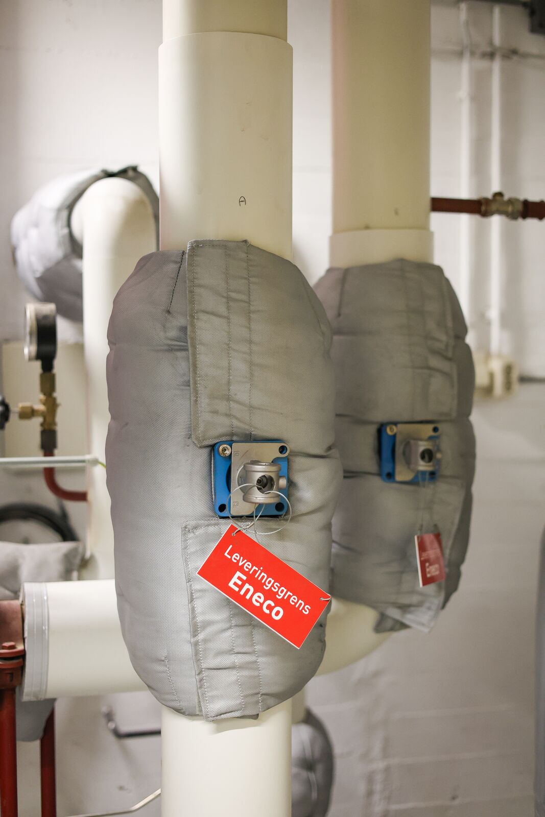 Zilvergrijze isolatiematrassen rond afsluiters in een technische ruimte